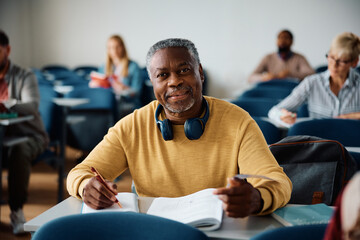 Wall Mural - Smiling black mature man studying while attending adult education training class and looking at camera.