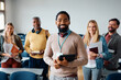 © Drazen - Happy black adult education teacher with group of students in classroom looking at camera.