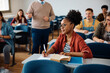 © Drazen - Black female student taking notes during class in lecture hall.