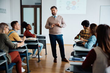 mature teacher giving lecture to university students in classroom.