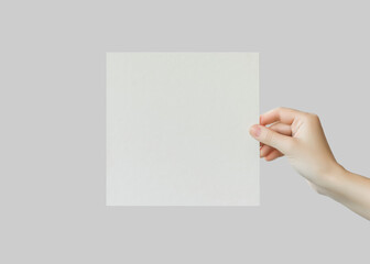 Wall Mural - female hand holds empty square cardboard banner on grey background. empty space for text