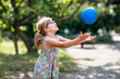 Little preschool girl with eyeglasses playing with ball outdoors. Happy smiling child catching and throwing, laughing and making sports. Active leisure with children and kids. Summer day on backyard