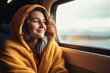 © Stavros - Journey alone with yourself and your thoughts. A young Caucasian woman rides a train, smiling thoughtfully, looking out the window. Digital detox and offline concept.