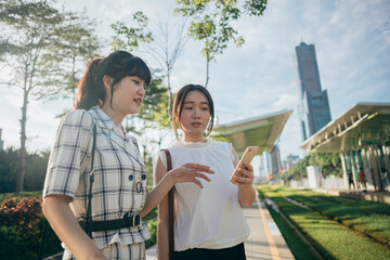 Two Asian business woman engage in a conversation on the street after their workday.