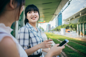 Two Asian businesswomen engage in a conversation on the street after their workday.