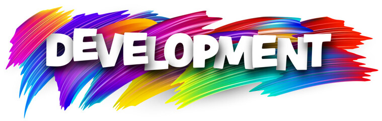 Development paper word sign with colorful spectrum paint brush strokes over white.