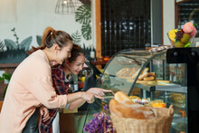 Customers Who Are Close Friends Come To Order Cakes In Cafe. Pointing At The Bakery In Bakery To Tell Staff Of The Shop To Bring Out Some Sweets For Them. Atmosphere In A Small Business Coffee Shop