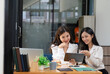 © bunyiam - Two happy young women discussing business while working together at the creative office