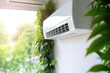 © Lazy_Bear - Air conditioner on wall in living room with green home plants, close up. Adjusting comfort temperature in home at hot summer, cooling air in the room