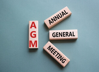 AGM - Annual general meeting symbol. Concept word AGM on wooden cubes. Beautiful grey green background. Business and AGM concept. Copy space.