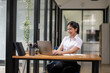 © Wasana - Young businesswoman working on laptop in corporate office.
