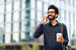 © Prostock-studio - Young eastern businessman talking on phone while walking by street