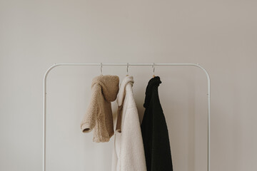 Wall Mural - Fluffy woolen baby and adult jackets on hanger. Minimalist fashion wardrobe background