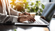 © MUNTHITA - Hands of a young contemporary office manager sitting and typing on a laptop keyboard during work in the office.
