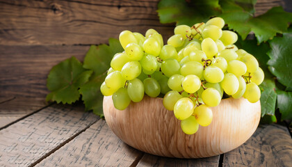 Wall Mural - Bunch of green ripe grapes in a wooden bowl, on rustic wood background