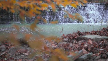 Wall Mural - Colorful waterfall in autumn with slow motion cascade and fall covered leaves