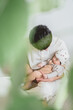 秋のお昼、部屋の中で赤ちゃんを膝に乗せて抱っこするお父さんと眠そうにしているチェリー柄の帽子を被った日本人の幼児