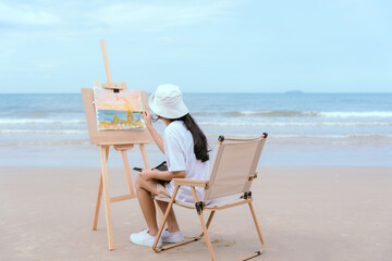 Asian girl painting in watercolor on the beach