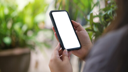 Wall Mural - closeup view of woman using smartphone while sitting in summer garden.