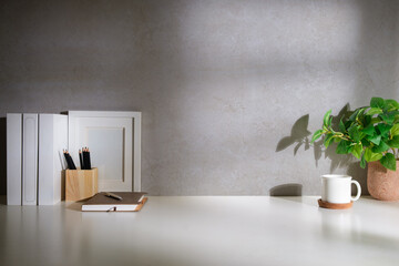 Wall Mural - Home office interior. Houseplant, coffee cup, books and pencil holder on white table.