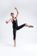 © danmorgan12 - Sports Ideas. Athletic Caucasian Ballet Dancer Man Posing in Dancing Stretching Pose With Hands Lifted Up in While Standing on Feet in Black Tights On White.