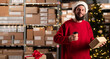 Portrait of male worker holding box inside warehouse drinking takeaway coffee and looking at camera.