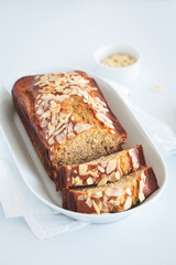 Wall Mural - Banana bread with almonds on a white plate on white background.