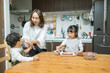 春の日中の自宅のキッチンで3人で楽しそうにケーキ作りを行う日本人の親子