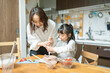 春の部屋でテーブルでお菓子を作る日本人の30代の女性と小学生の子供