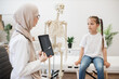 © sofiko14 - Radiologist showing x-ray results on tablet to kid in clinic