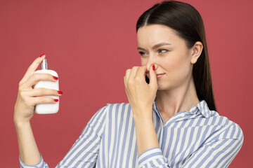 Wall Mural - Dissatisfied woman with perfume bottle  in hand on pink background