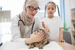 © sofiko14 - Animal doctor testing cat's eyes with tween guardian behind