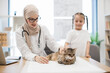 © sofiko14 - Female specialist and owner stroking cat during vet exam
