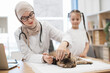 © sofiko14 - Pet care professional making injection to cat near tween kid