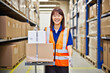 © InputUX - Asian female warehouse employee managing inventory, holding boxes with shelves in the background, streamlining shipping and logistics operations and efficiency