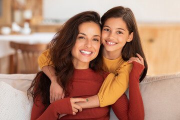 portrait of happy arab woman and daughter hugging at home