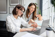 © Prostock-studio - Joy of teamwork. Female coworkers using laptop, woman pointing at screen and discussing work project together in office