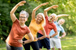 © Prostock-studio - Group of sporty mature people doing stretching exercises at park