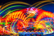 © ON-Photography - Merry-go-round at night with many colorful LED light traces. Long time exposure that leaves abstract circular moving light lines and paintings on a funfair in Germany. Turning joyride or carousel.