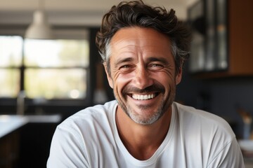 Handsome middle age man with beard wearing casual clothes at home in kitchen background. Happy face smiling, looking at the camera. Positive person.