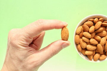 Wall Mural - Woman holding organic almond nut in hands. Nutrition healthy food choice concept. Calories dieting snack. Sustainable lifestyle. Close-up