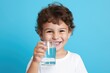© Оксана Олейник - Cute little boy drinking water from glass on blue bg