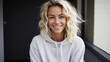 Young adult stylish smiling blonde European woman, beautiful teen girl pretty gen z model with curly blond hair wearing hoodie looking at camera, close up face street style portrait outdoors.