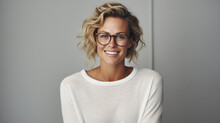 Young Adult Stylish Confident Attractive Smiling Blonde European Business Woman, Beautiful Lady Pretty Model With Curly Blond Hair Wearing Glasses Looking At Camera, Close Up Face Portrait Indoors.