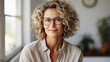 © Synthetica - Mid aged adult confident European business woman with blonde curly hair, smiling middle aged lady blond model wearing eyeglasses looking at camera at home or in office, close up face portrait.