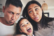 © Azee/peopleimages.com - Selfie, silly and portrait of girl with her parents bonding in the living room of their home. Goofy, happy and child taking a picture with her mother and father with funny faces at their family house