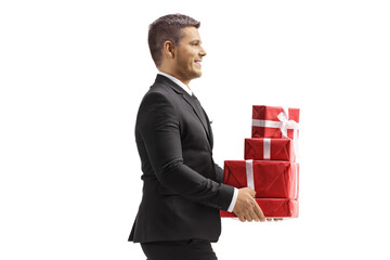 Wall Mural - Profile shot of a man in black suit walking and carrying a pile of presents