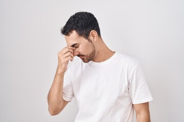 Sticker - Handsome hispanic man standing over white background tired rubbing nose and eyes feeling fatigue and headache. stress and frustration concept.