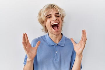 Sticker - Young modern man standing over isolated background celebrating mad and crazy for success with arms raised and closed eyes screaming excited. winner concept