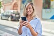 © Krakenimages.com - Young blonde woman smiling confident using smartphone at street